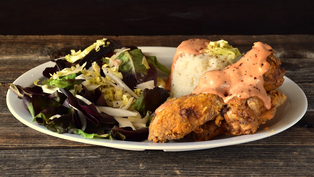 A plate of chicken rice with sliced cucumber and greens
